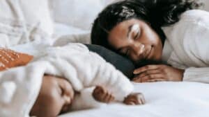 Toronto new mom sleeping with baby on bed